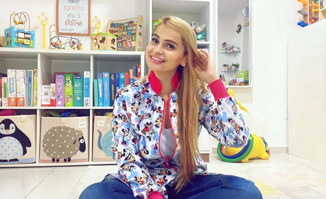 Priscila sentada no chão do consultório, entre brinquedos