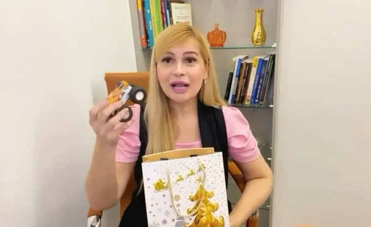 Priscila tirando um brinquedo de uma sacola surpresa